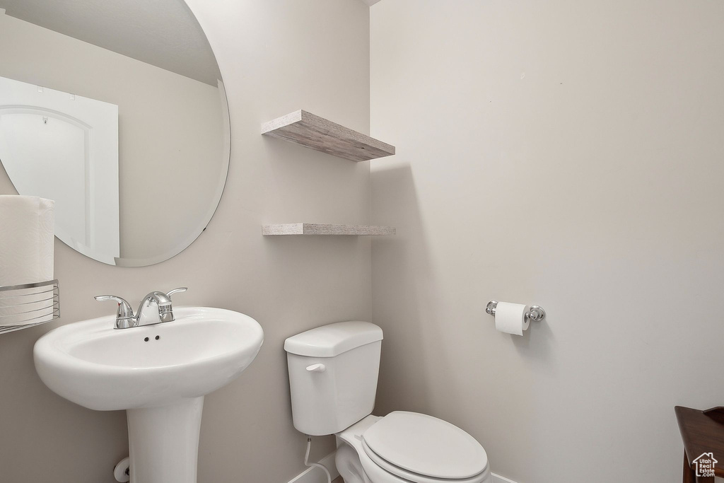 Bathroom with toilet, baseboards, and a sink