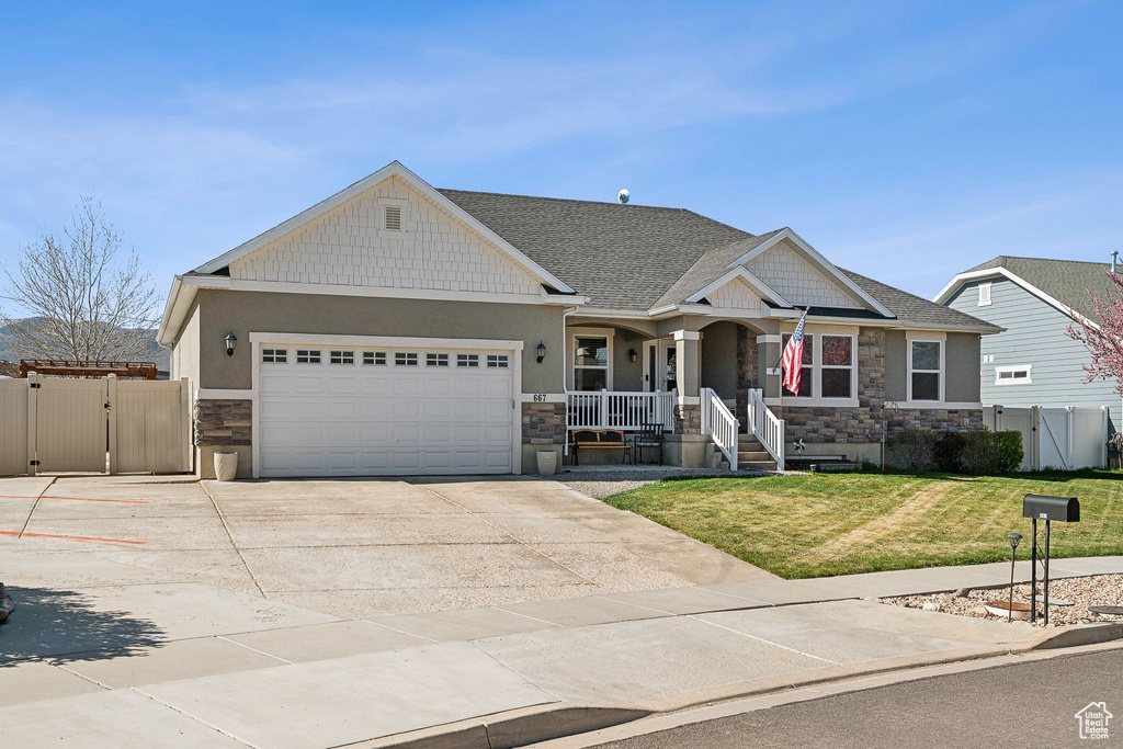 Craftsman house with a gate, a porch, stone siding, a garage, and a front yard