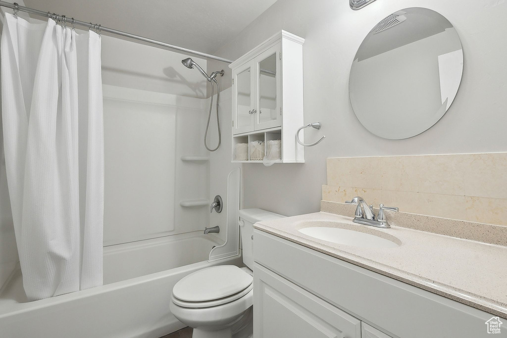 Full bathroom with shower / bath combo with shower curtain, toilet, and vanity