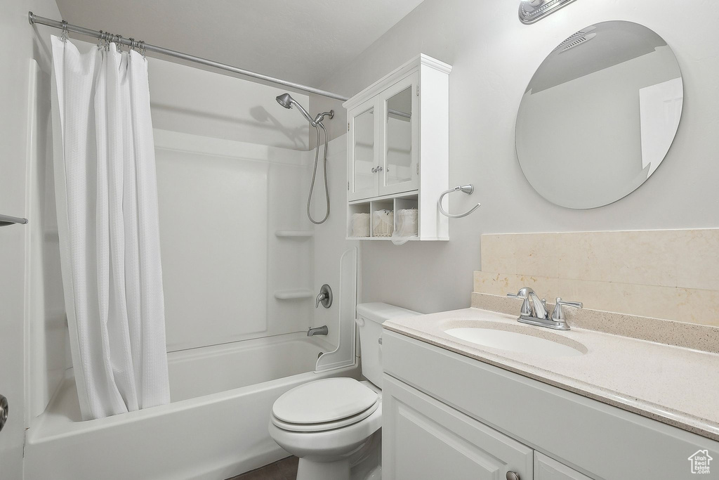 Bathroom with shower / bath combo with shower curtain, toilet, and vanity