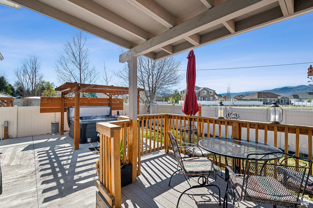 Wooden terrace with a residential view, outdoor dining area, a hot tub, a fenced backyard, and a patio area