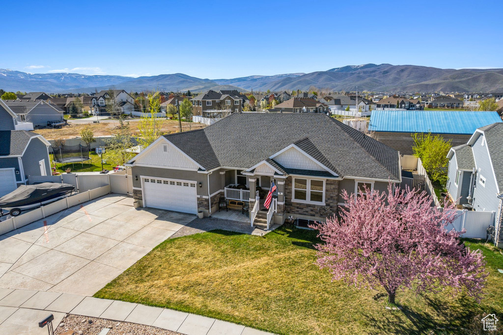 View of front of property featuring stone siding, fence, a garage, and a residential view