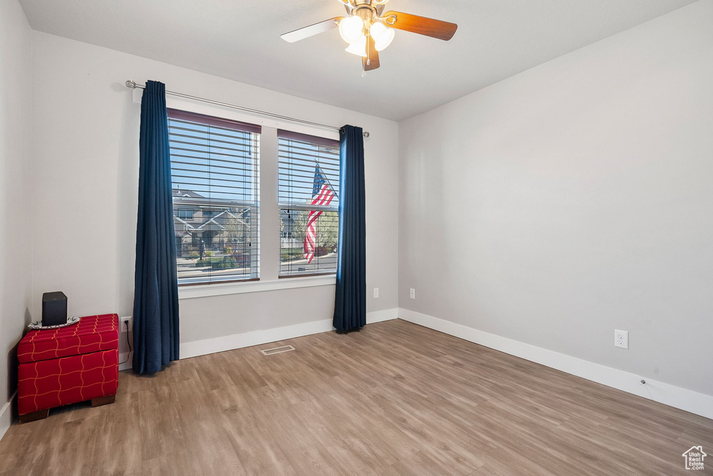 Spare room featuring baseboards, a ceiling fan, visible vents, and wood finished floors