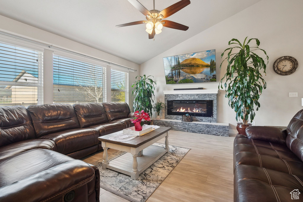 Living room featuring a fireplace, a ceiling fan, high vaulted ceiling, and wood finished floors
