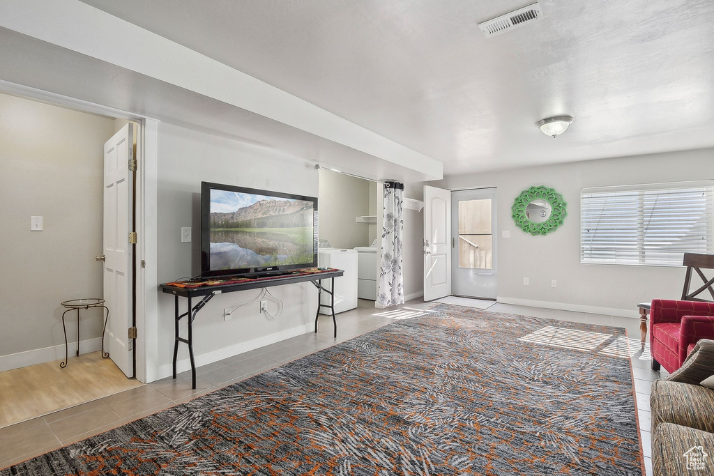 Living area with baseboards, tile patterned floors, washer and dryer, and visible vents