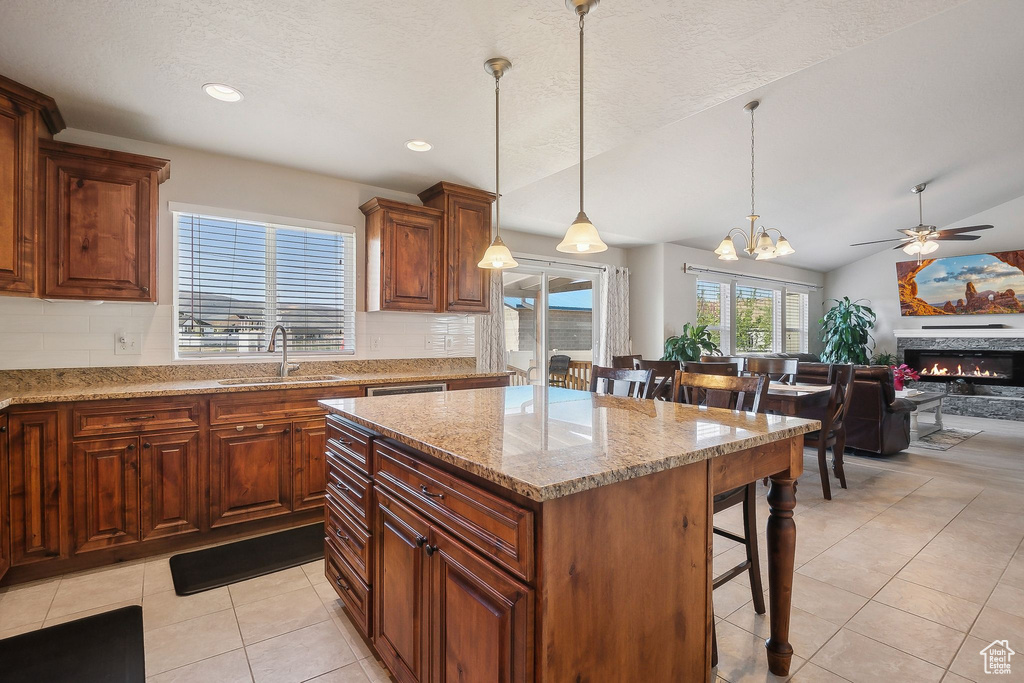 Kitchen featuring light tile patterned flooring, tasteful backsplash, a kitchen breakfast bar, and a sink