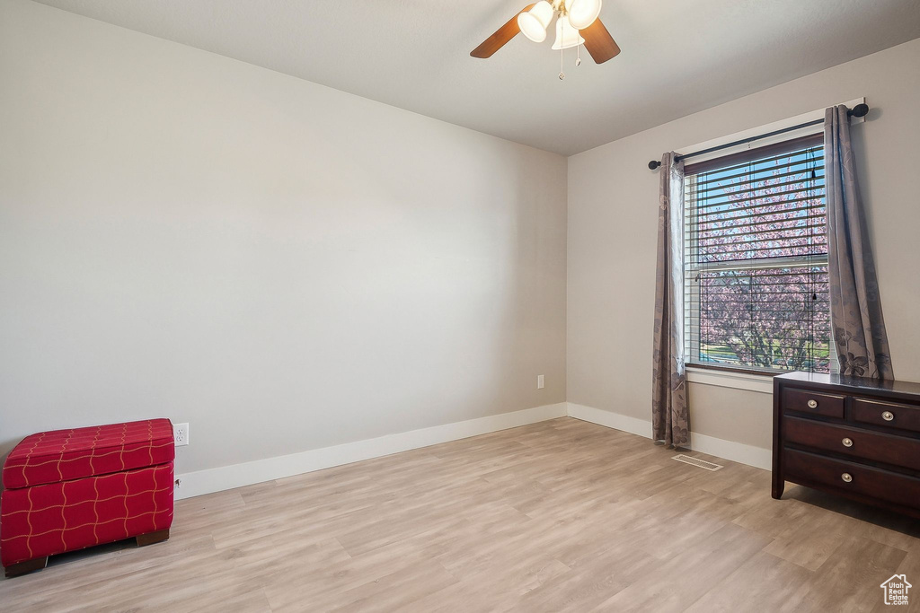 Empty room with light wood-type flooring, baseboards, visible vents, and a ceiling fan