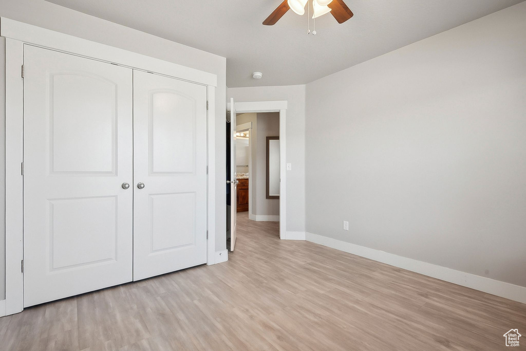 Unfurnished bedroom featuring baseboards, a closet, a ceiling fan, and light wood-style floors