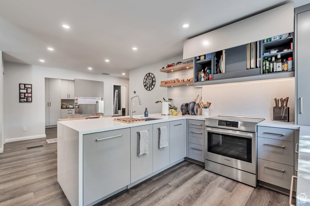 Kitchen with a peninsula, a sink, stainless steel electric range, and gray cabinets
