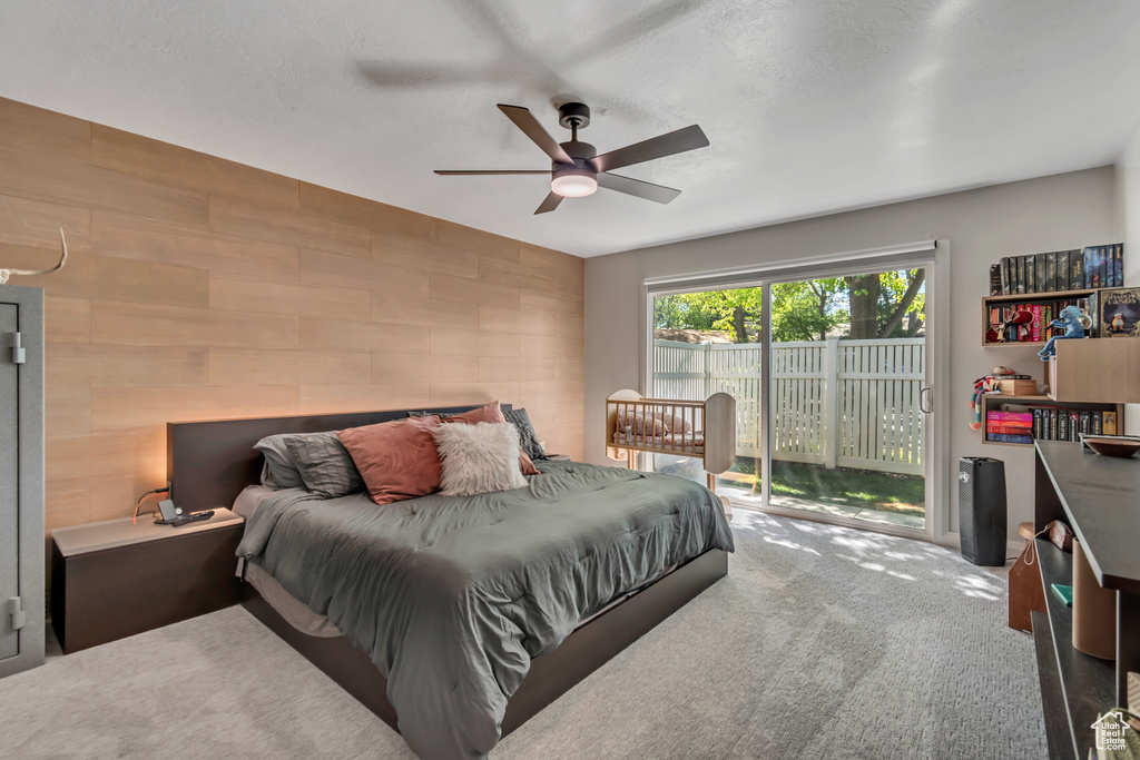 Carpeted bedroom with access to outside, ceiling fan, and an accent wall