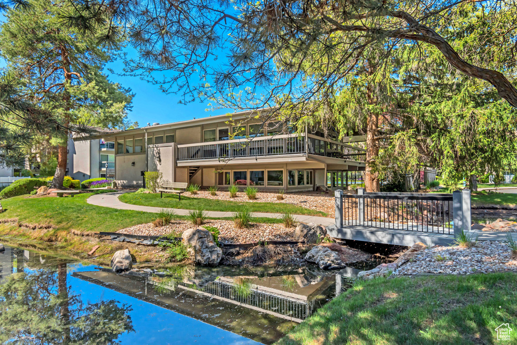 Rear view of house featuring stucco siding, a lawn, and a balcony