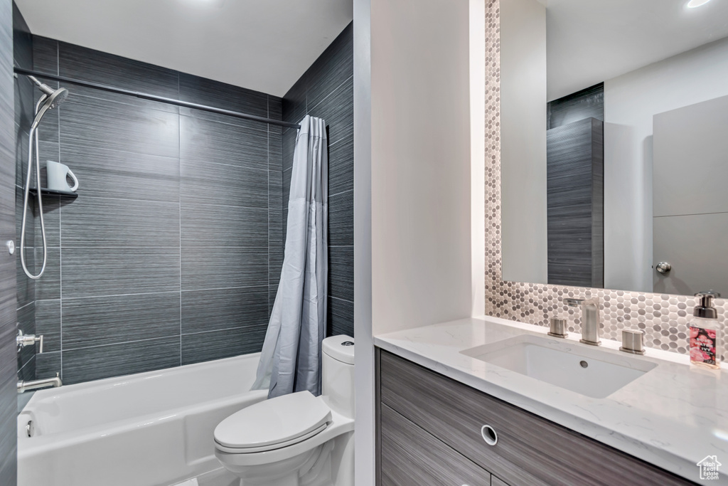 Full bathroom featuring vanity, toilet, decorative backsplash, and shower / bath combo