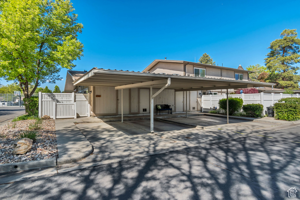 View of front of home featuring covered parking, fence, and a gate