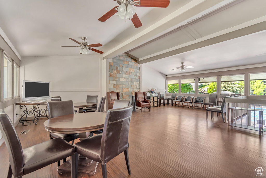 Dining space featuring wood finished floors, a ceiling fan, and vaulted ceiling with beams