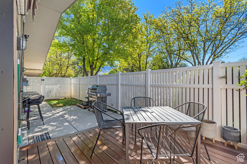 Wooden terrace featuring a fenced backyard, outdoor dining space, and a grill