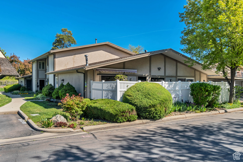 View of property exterior featuring stucco siding, an attached garage, and fence
