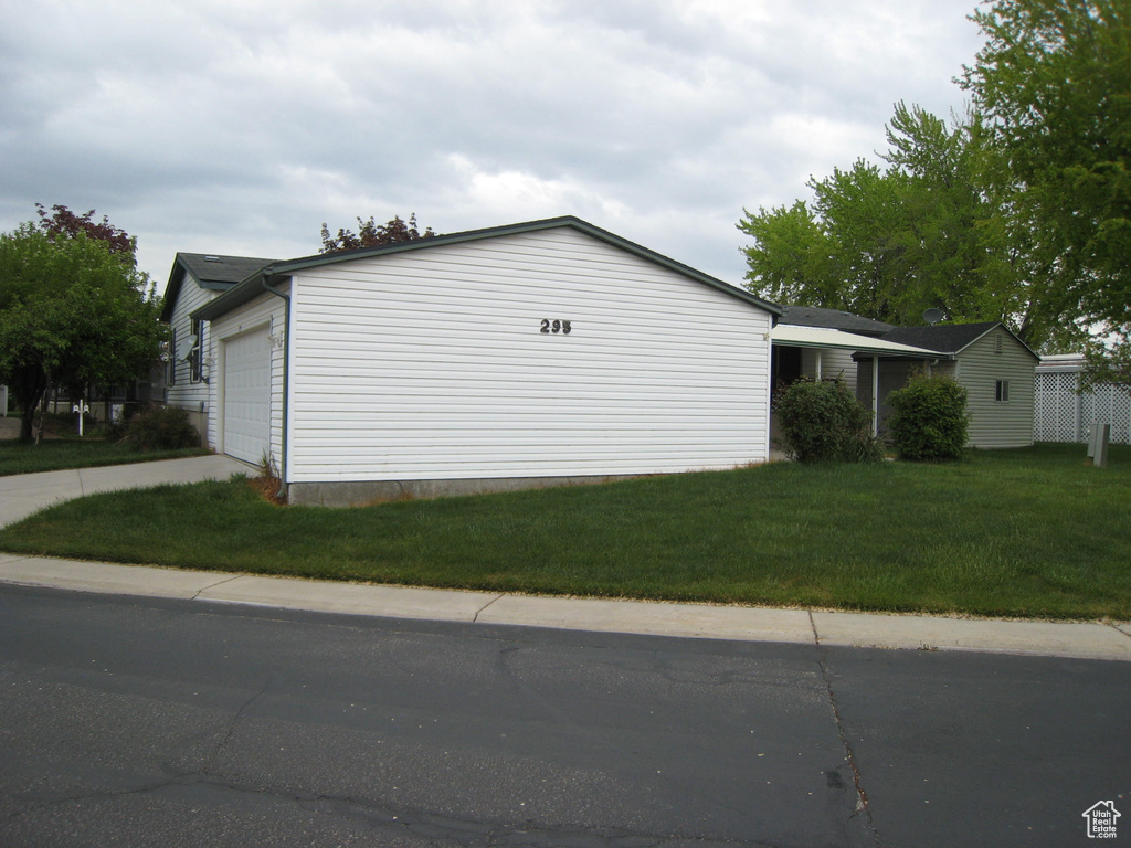 View of side of property featuring a yard and concrete driveway