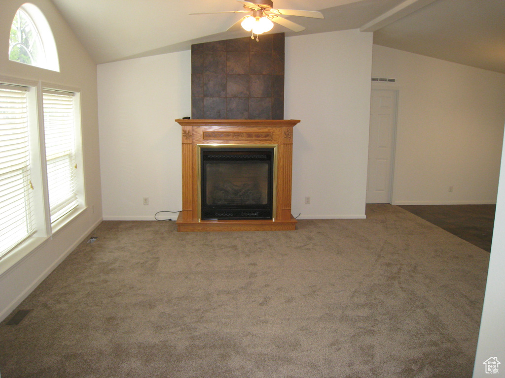 Unfurnished living room featuring a ceiling fan, carpet flooring, a large fireplace, and vaulted ceiling