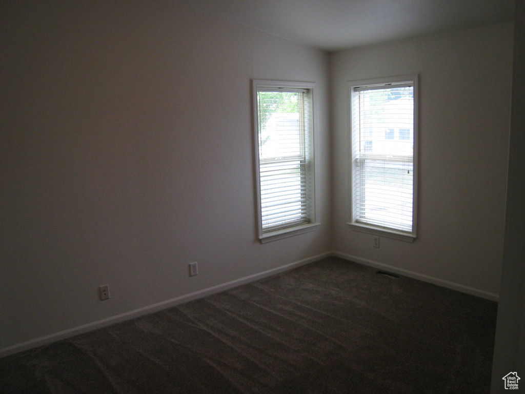 Unfurnished room featuring baseboards, lofted ceiling, and dark colored carpet