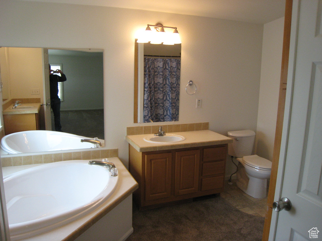 Bathroom featuring a garden tub, toilet, and vanity