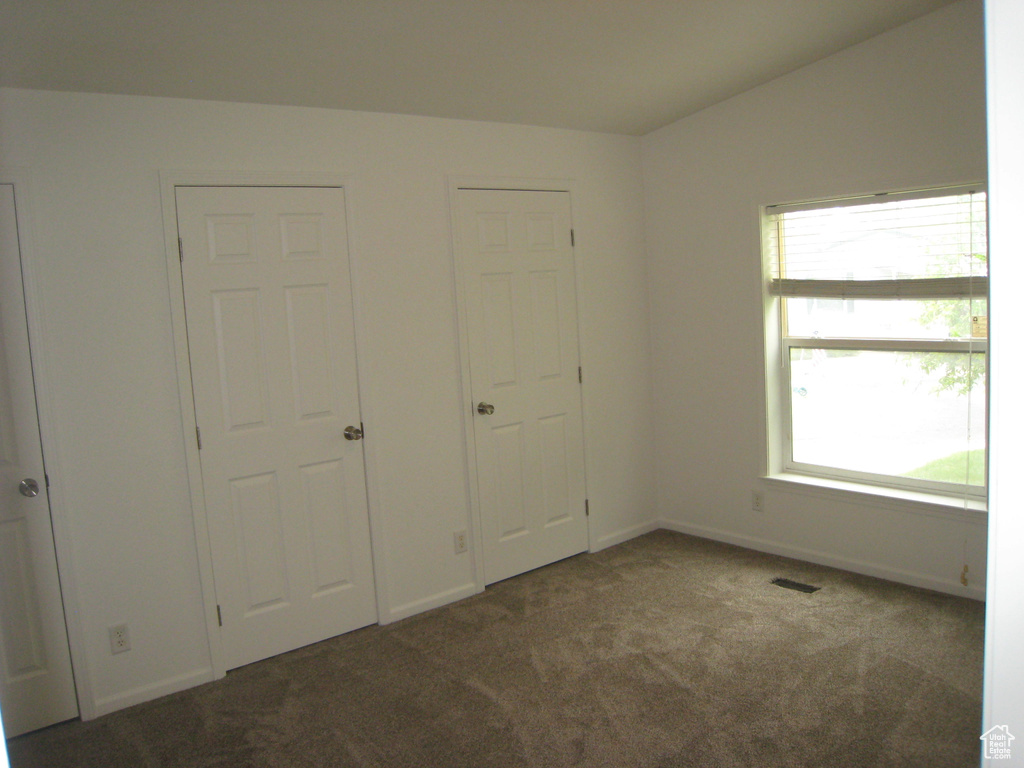 Unfurnished bedroom with carpet floors, baseboards, visible vents, and multiple windows