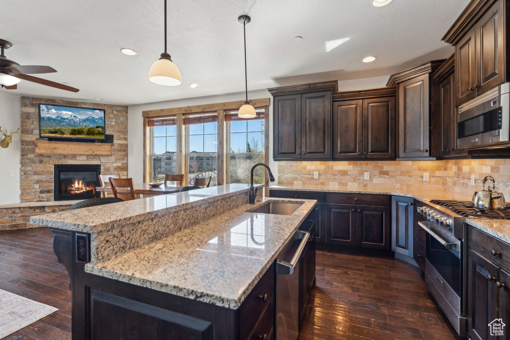 Kitchen featuring a sink, appliances with stainless steel finishes, ceiling fan, and dark wood-style floors