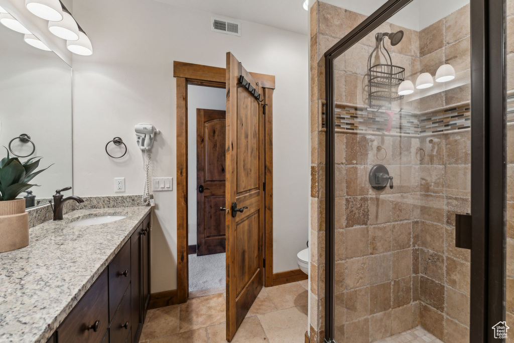 Full bath featuring vanity, a shower stall, and visible vents