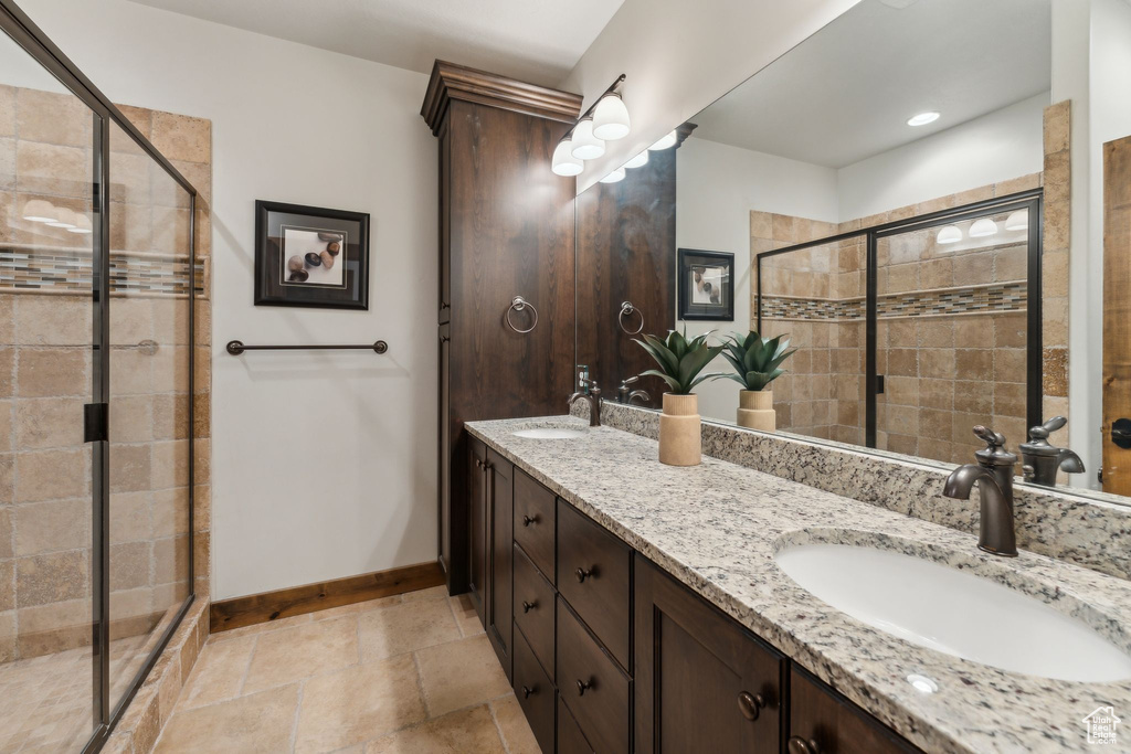 Bathroom featuring double vanity, a sink, baseboards, and a stall shower