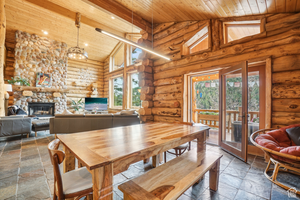 Dining room featuring wood ceiling, log walls, stone tile floors, and high vaulted ceiling