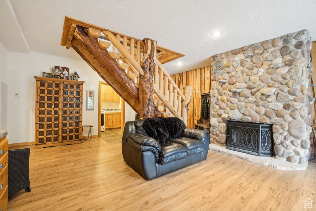 Living room with stairs, wood walls, wood finished floors, recessed lighting, and a fireplace