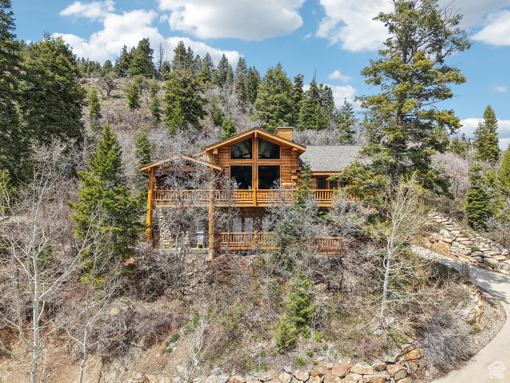 Exterior space featuring a chimney, a deck, and log siding