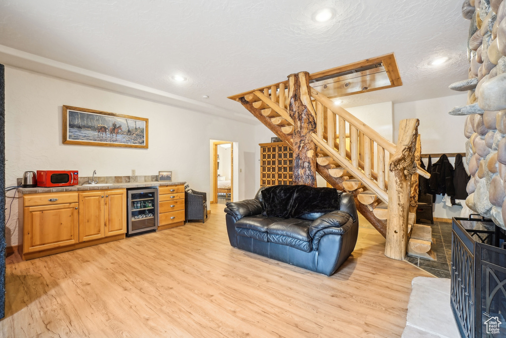 Living room with recessed lighting, beverage cooler, indoor wet bar, stairway, and light wood-type flooring