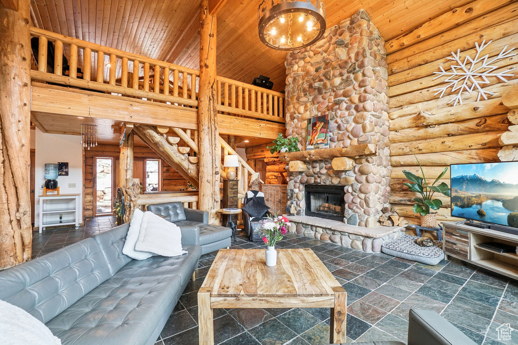 Living area featuring high vaulted ceiling, stairway, a fireplace, wood ceiling, and rustic walls