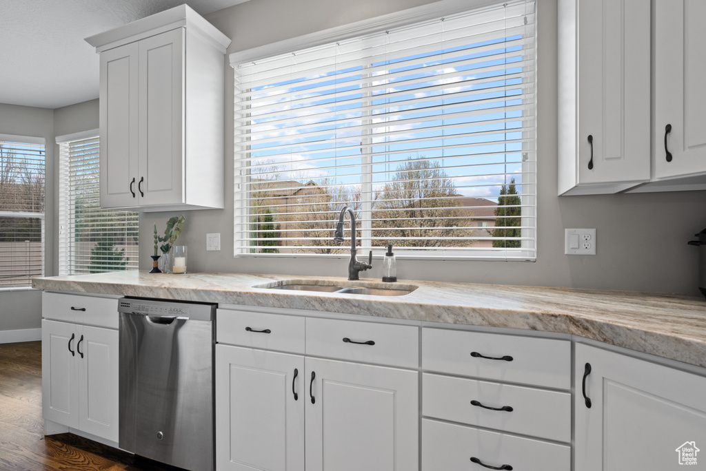 Kitchen with dishwasher, plenty of natural light, white cabinetry, and a sink