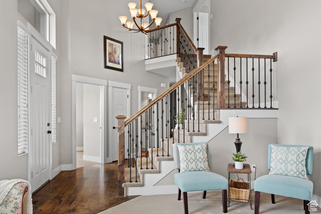 Entrance foyer with stairway, a chandelier, a towering ceiling, and wood finished floors