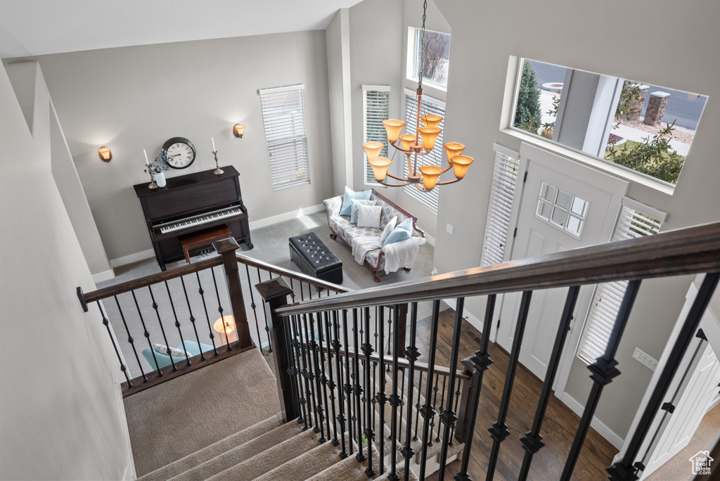 Staircase with a high ceiling, a notable chandelier, baseboards, and wood finished floors