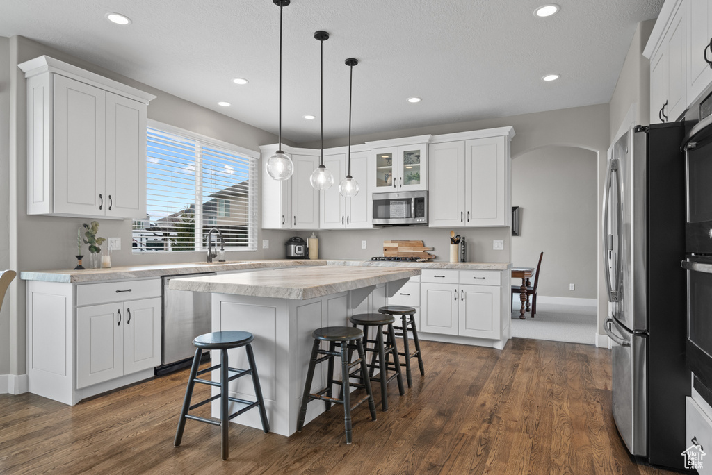 Kitchen featuring white cabinetry, stainless steel appliances, and a breakfast bar