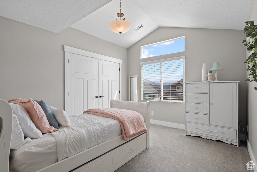 Bedroom with lofted ceiling, a closet, light colored carpet, visible vents, and baseboards