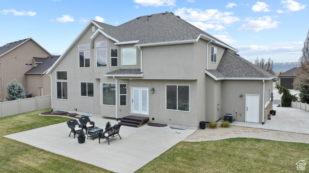 Rear view of house with a yard, fence, a patio area, stucco siding, and roof with shingles