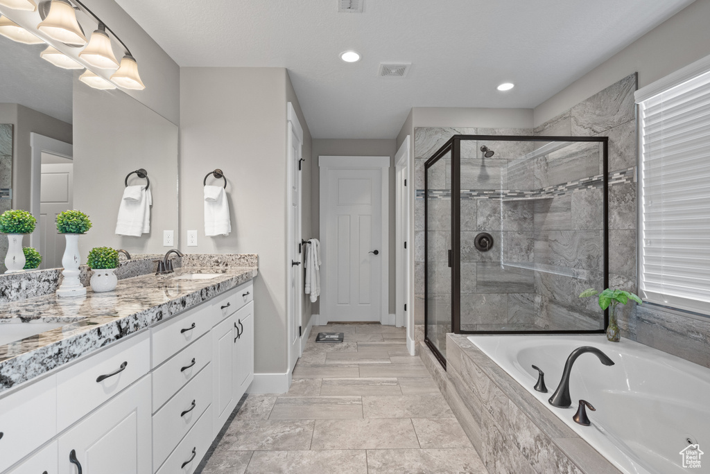 Full bath featuring a sink, visible vents, a shower stall, double vanity, and a garden tub