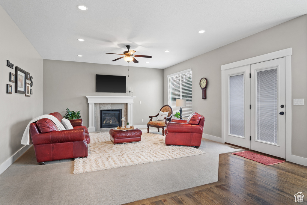 Living area with wood finished floors, a ceiling fan, a tiled fireplace, baseboards, and recessed lighting