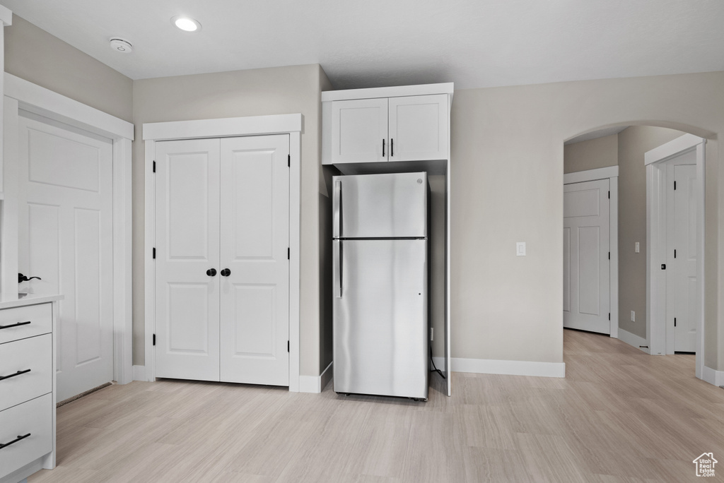 Kitchen featuring freestanding refrigerator, light wood-style floors, baseboards, and arched walkways