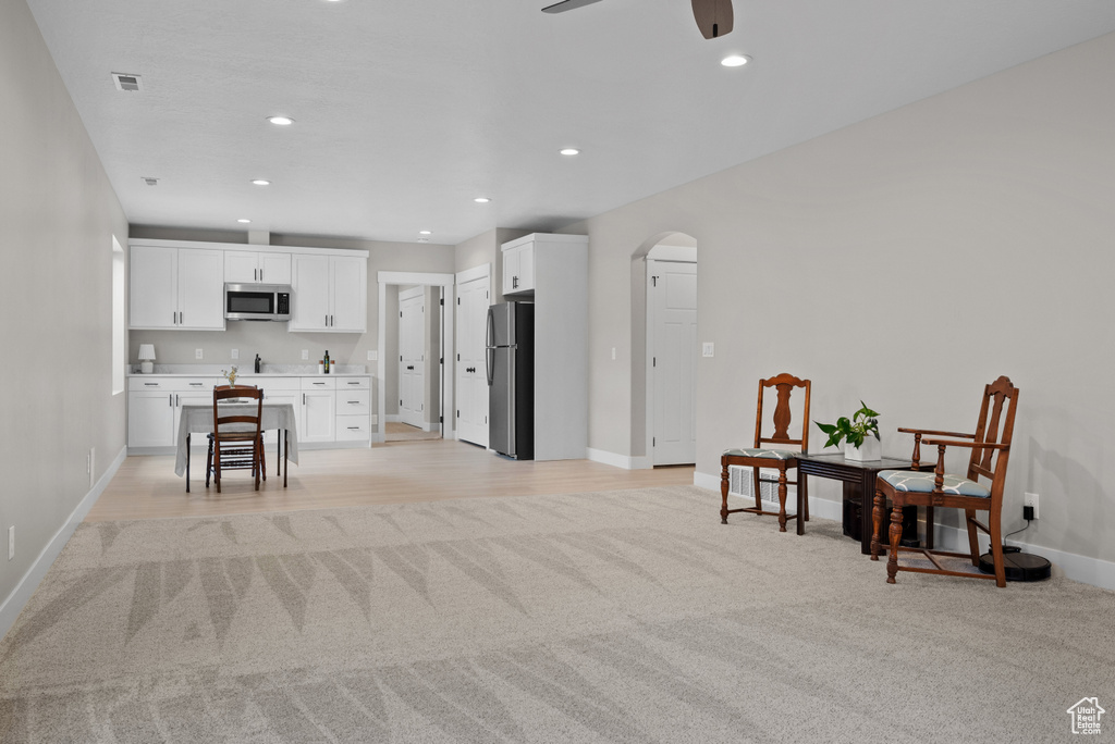 Sitting room with recessed lighting, ceiling fan, light carpet, arched walkways, and baseboards