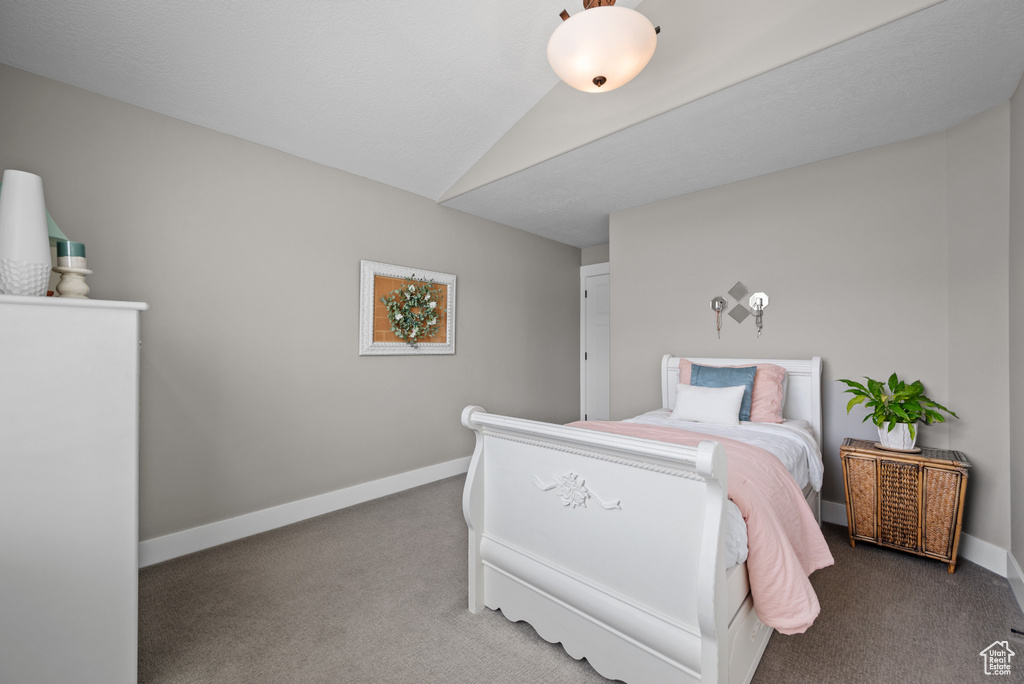 Carpeted bedroom with vaulted ceiling and baseboards