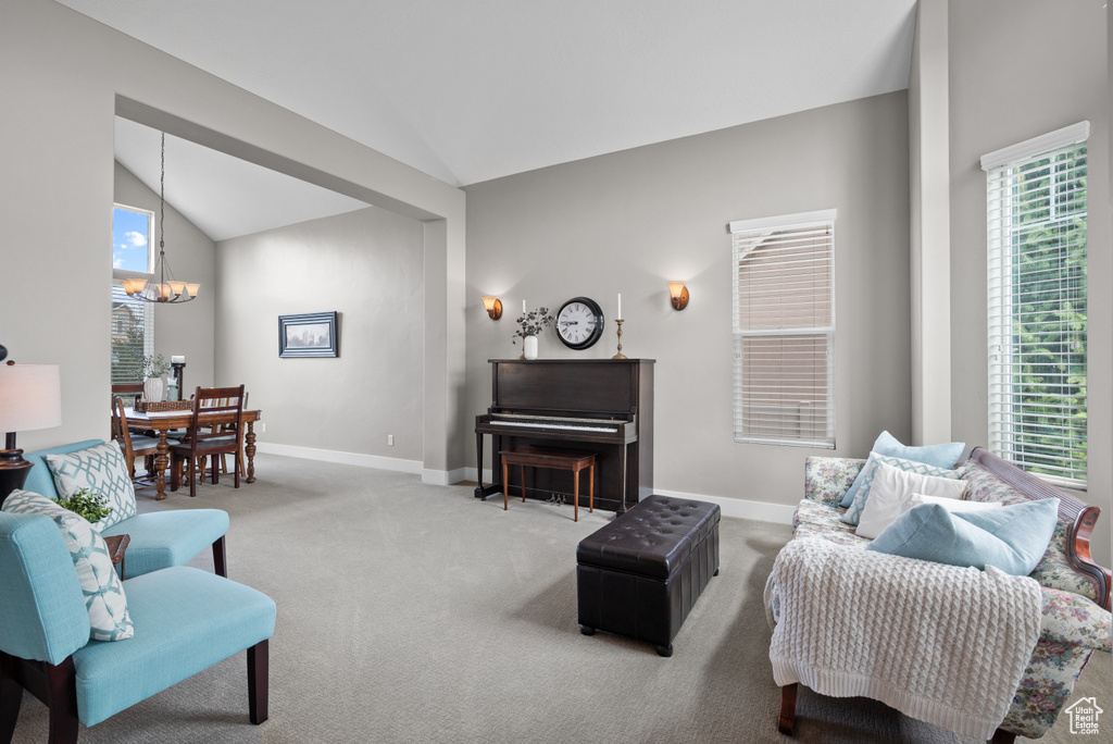Living room with vaulted ceiling, carpet floors, a notable chandelier, and baseboards