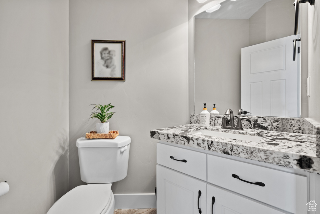 Bathroom with vanity, toilet, and baseboards