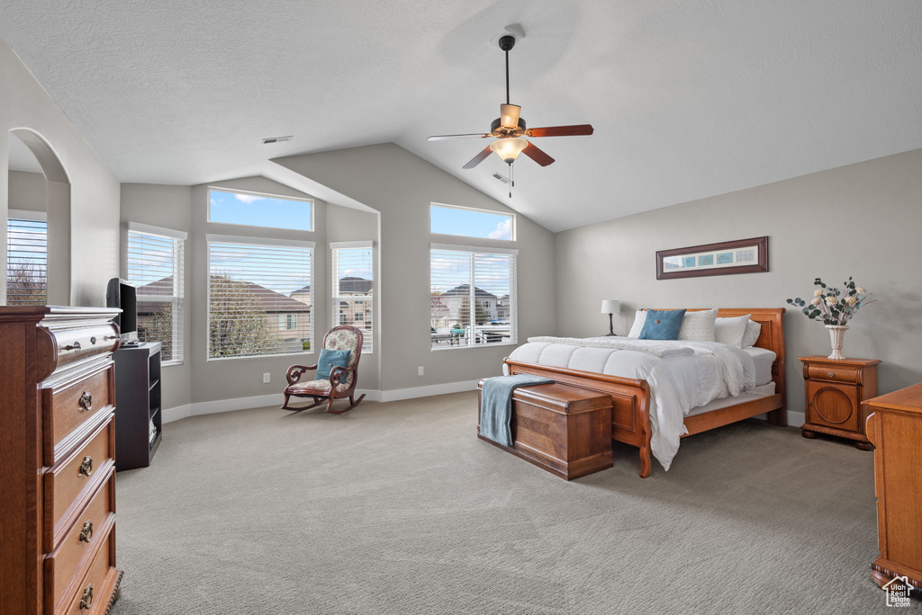 Bedroom with a ceiling fan, visible vents, baseboards, light colored carpet, and lofted ceiling