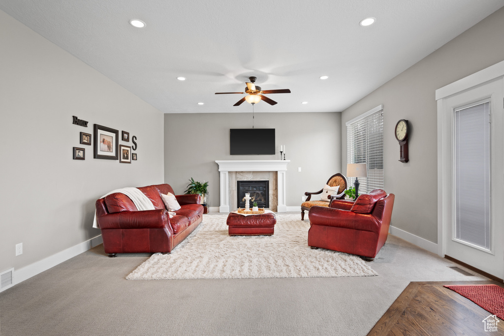 Carpeted living area featuring a tiled fireplace, baseboards, ceiling fan, and recessed lighting