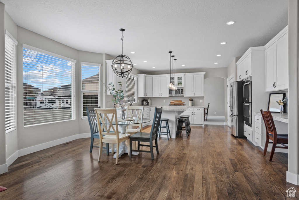 Dining space with recessed lighting, dark wood-style flooring, baseboards, and a notable chandelier