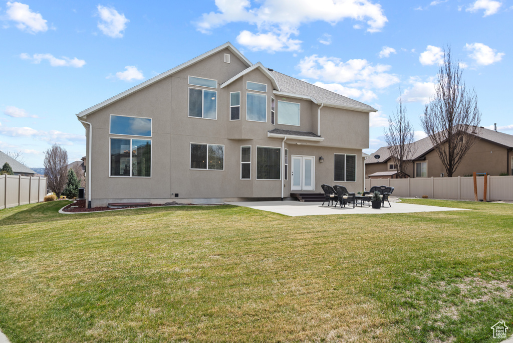 Rear view of property with a yard, a patio area, stucco siding, and fence